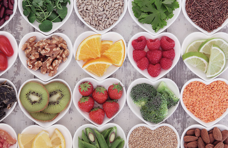 Heart-shaped bowls filled with colorful fresh fruits, nuts, and seeds.